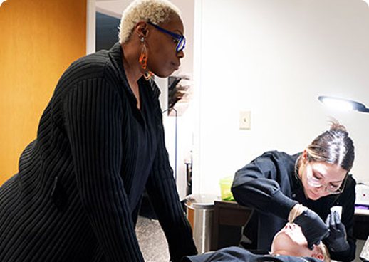 Esthetics teacher demonstrating eyebrow waxing techniques
